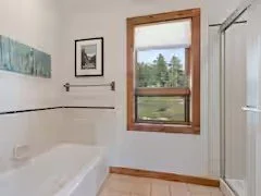 Bathroom with a window, bathtub, and shower enclosure
