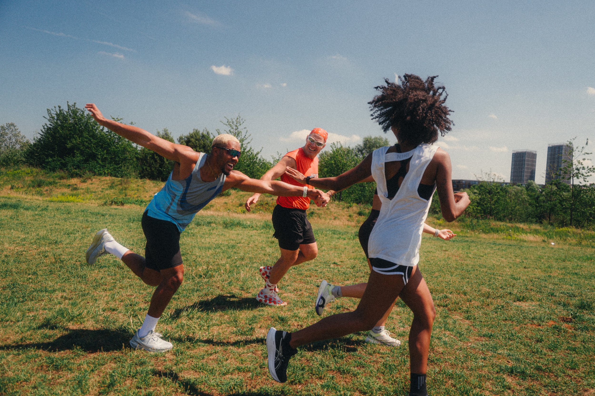 Team Marathon runners reaching out to each other mid run in an East London park