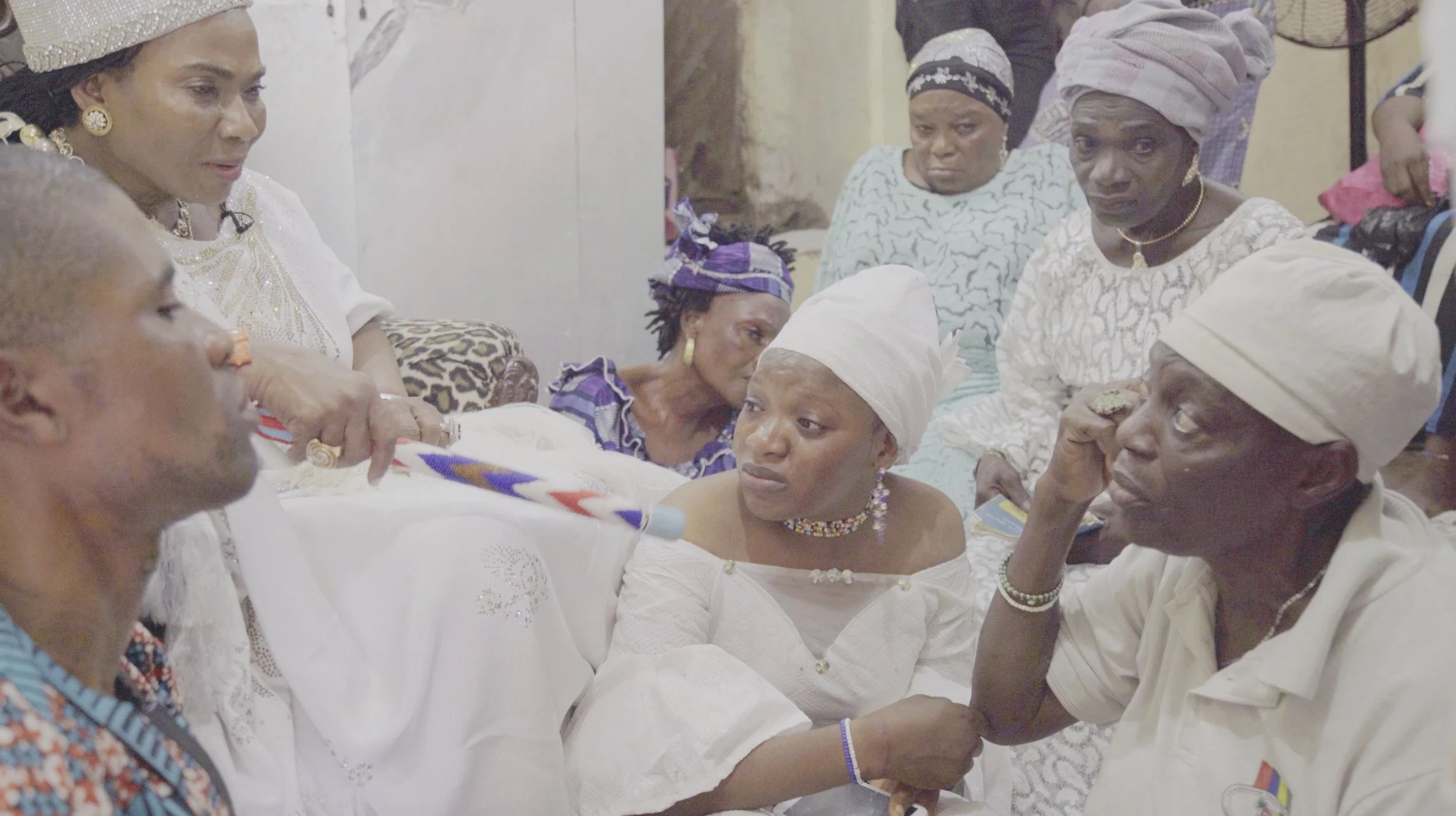 A group of women dressed in traditional clothing and headscarves gathered together indoors, possibly for a communal or social event.