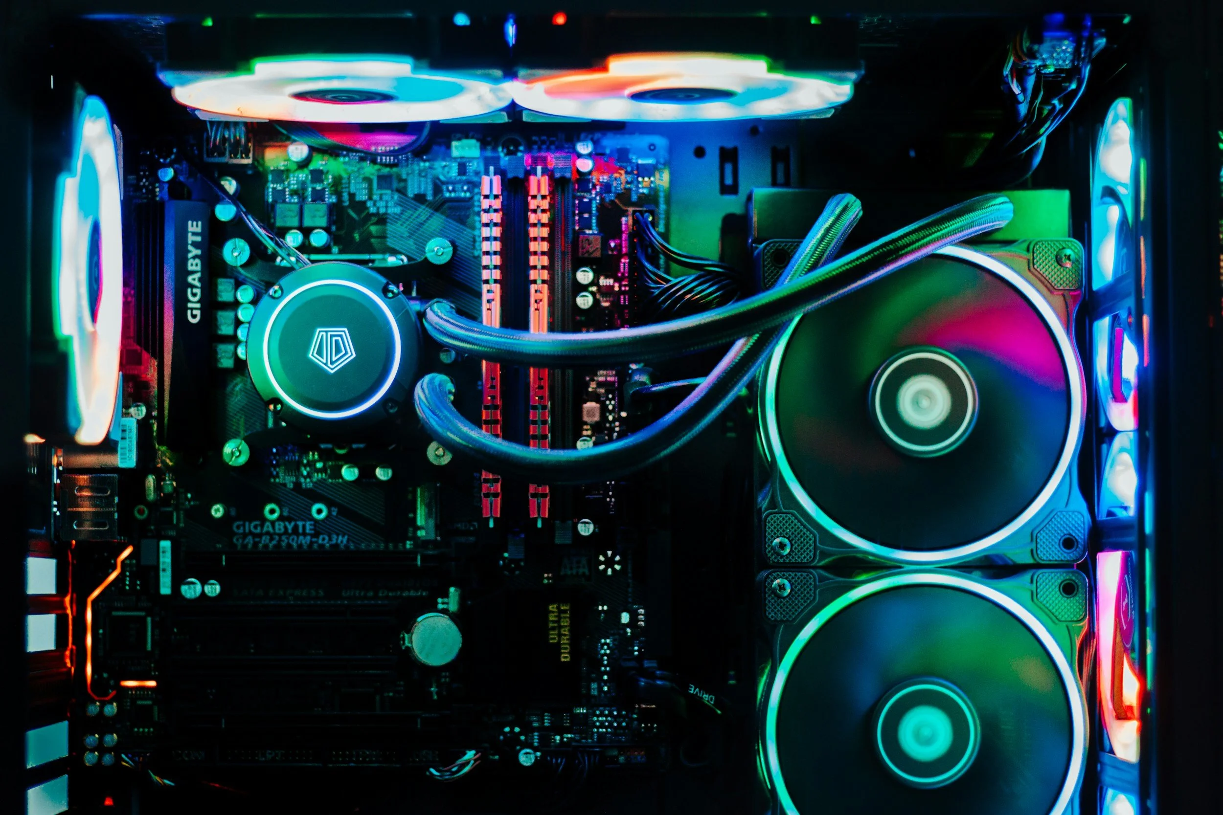 Inside view of a custom gaming computer showing illuminated RGB cooling fans, a motherboard, and various internal components.