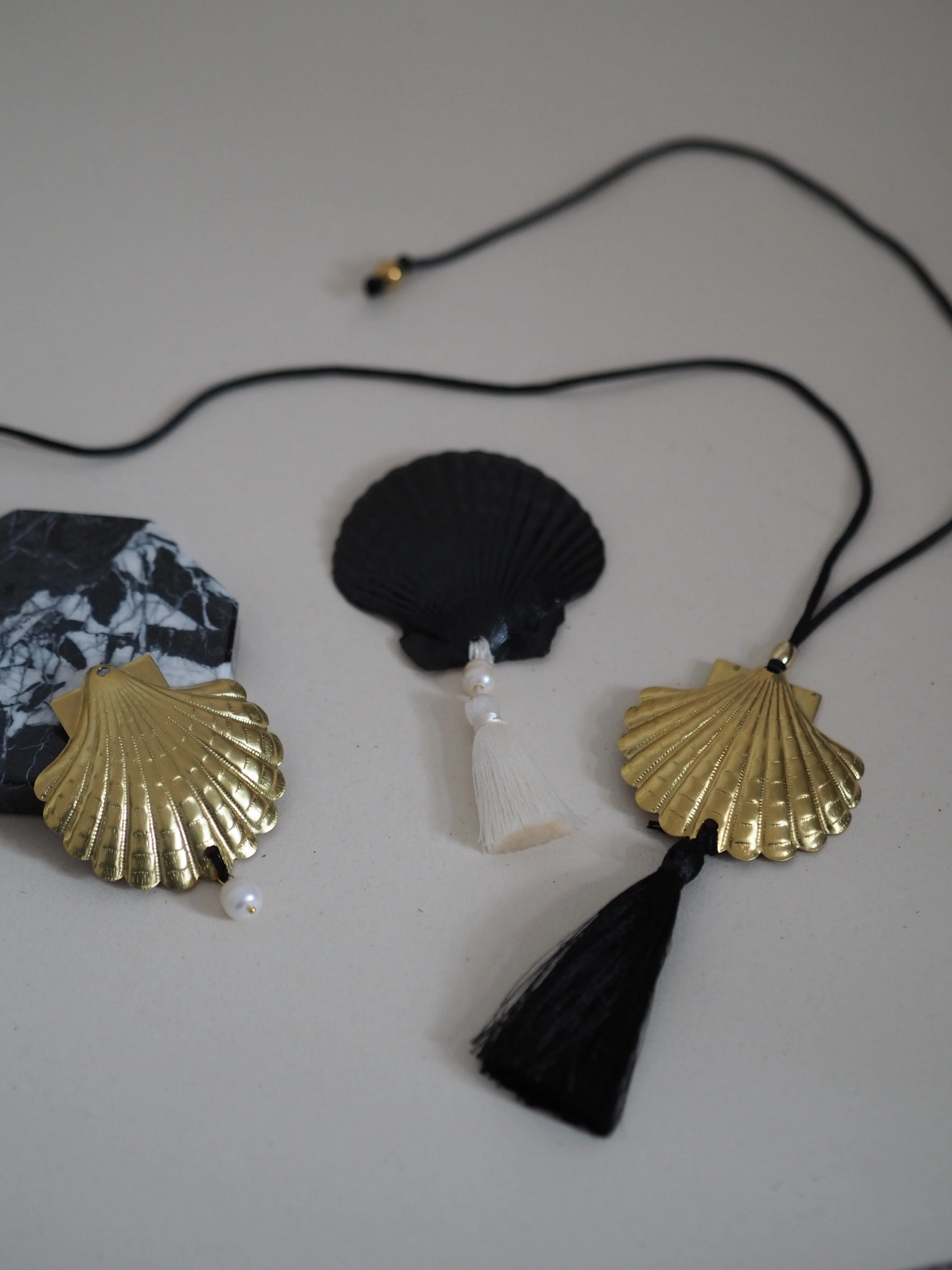 Schmuck mit Muscheldesigns, schwarzem Tuchband und Perlen, auf weißem Hintergrund