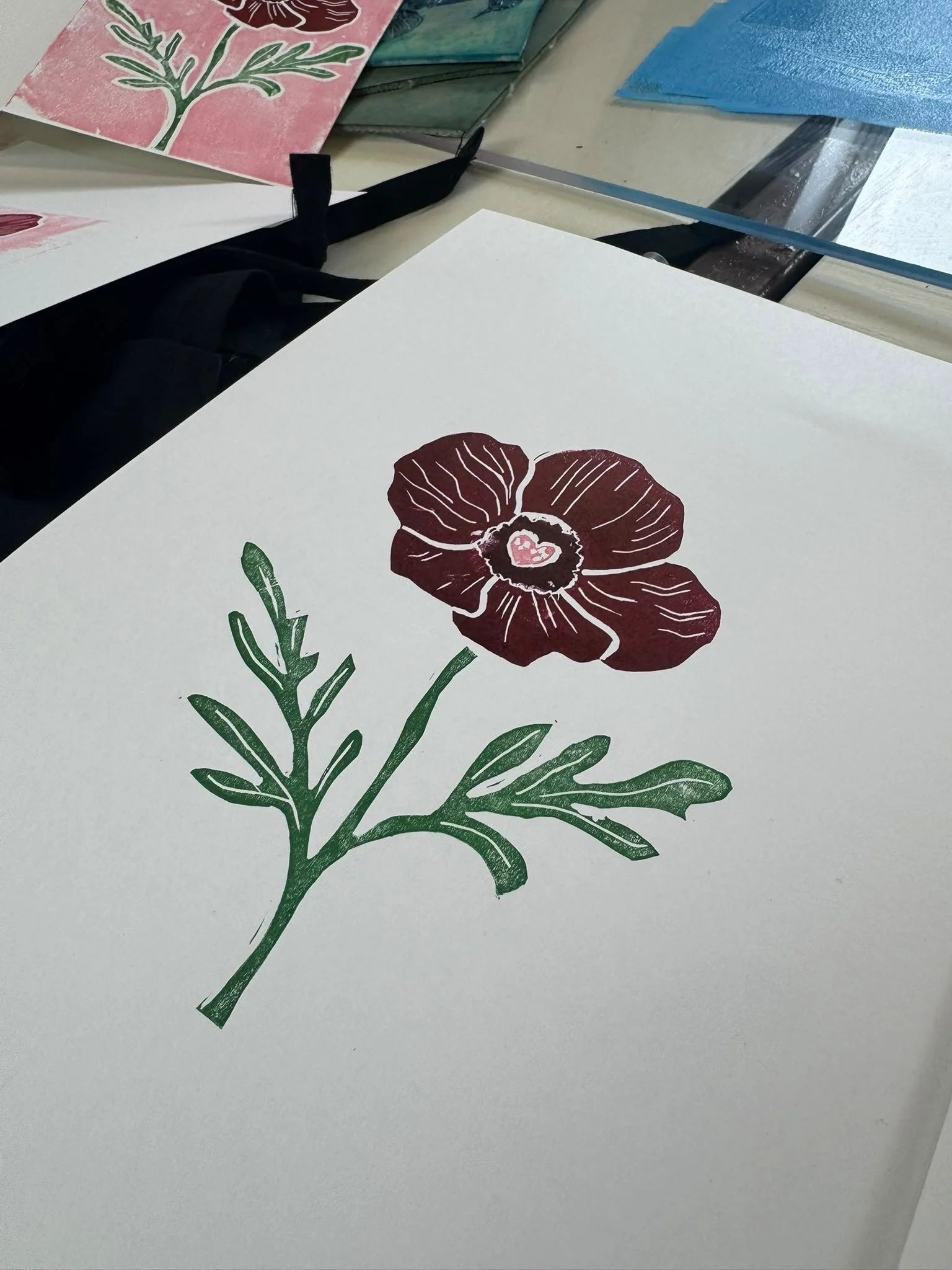 A white sheet of paper with a printed dark red flower and green leaves.