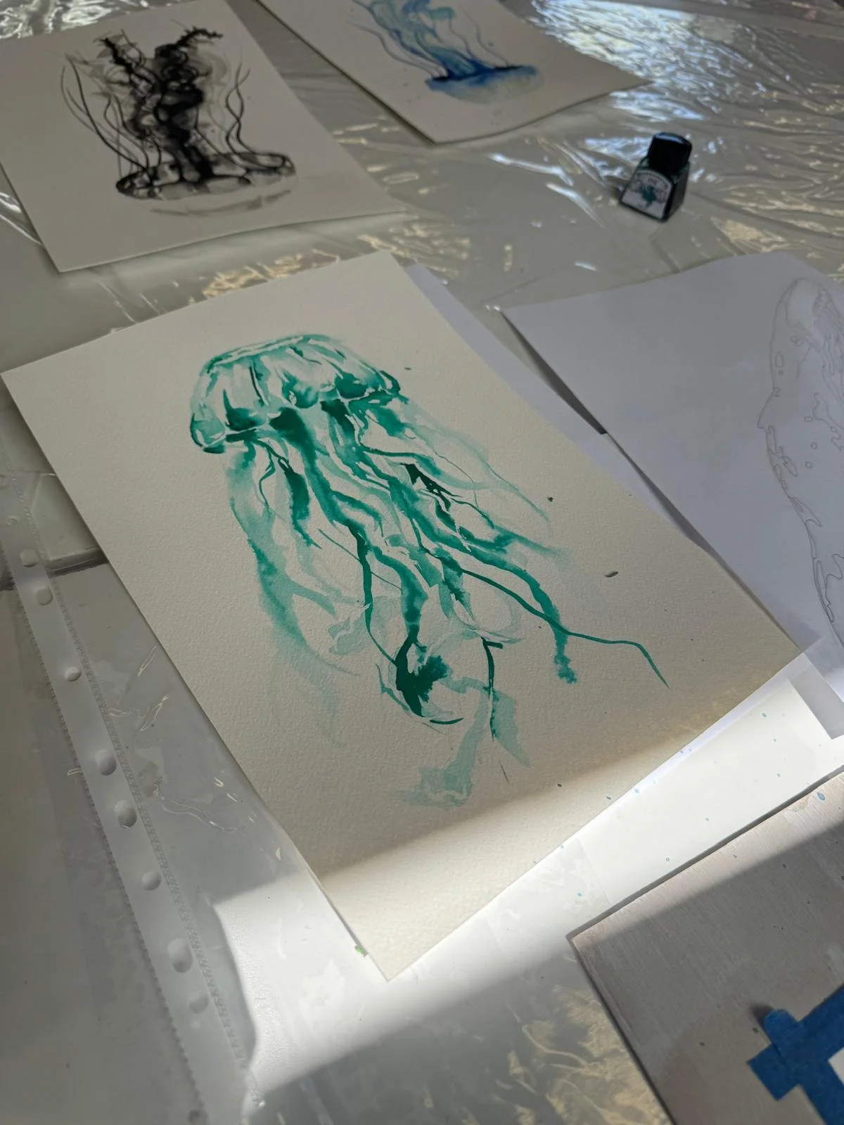 Watercolor painting of a jellyfish on textured paper, with blue and green hues.