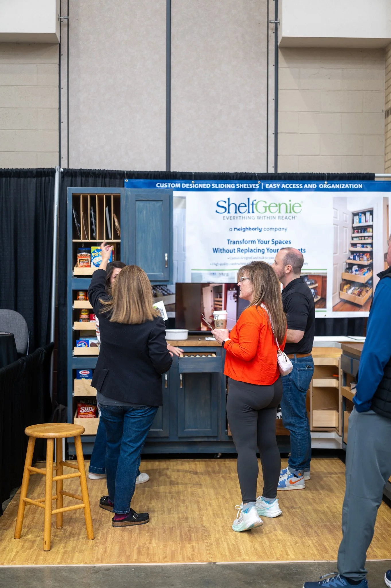 People standing around a display of custom sliding shelves at an expo.