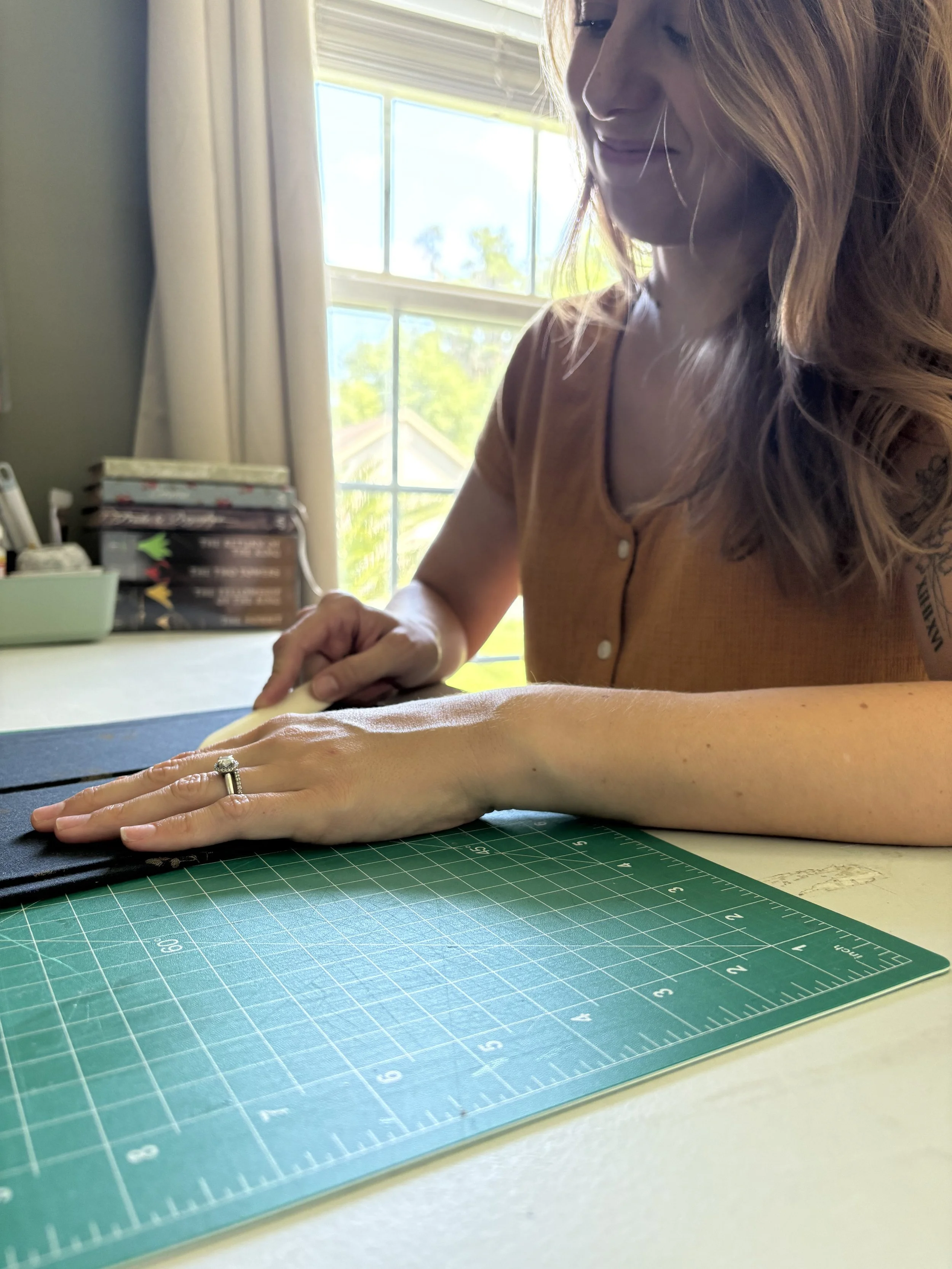 Lindsey, owner of Chasing Pines, using a bone folder to create a book casing