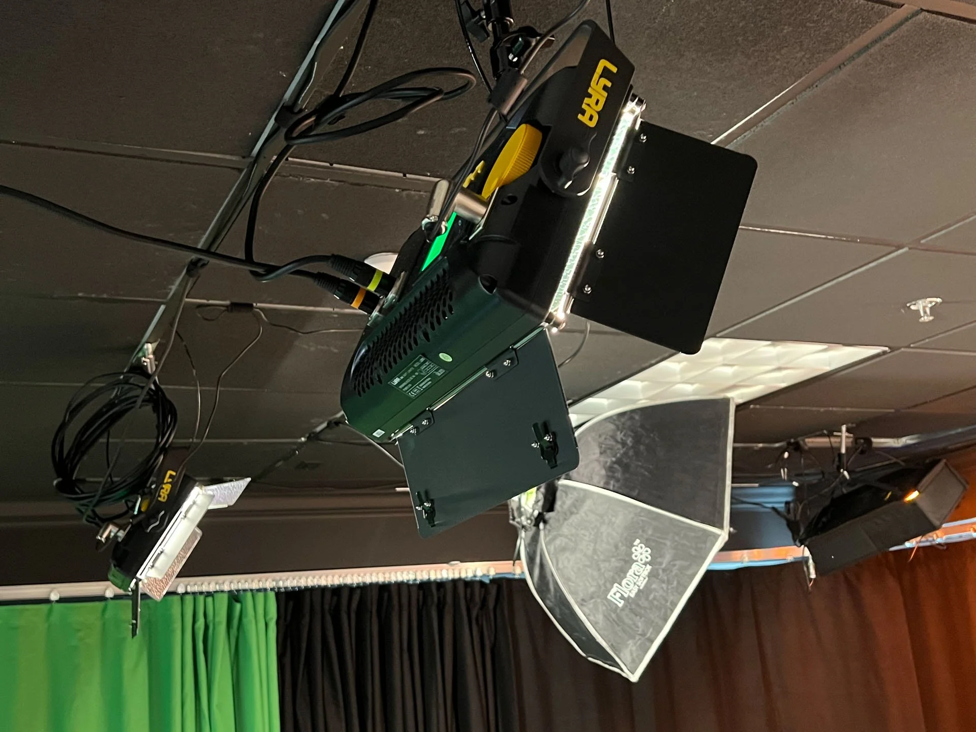 Photography studio setup with professional lighting, green and black backdrop, and camera on a tripod.