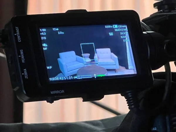 Camcorder screen showing a view of a living room with two armchairs and a round coffee table between them.