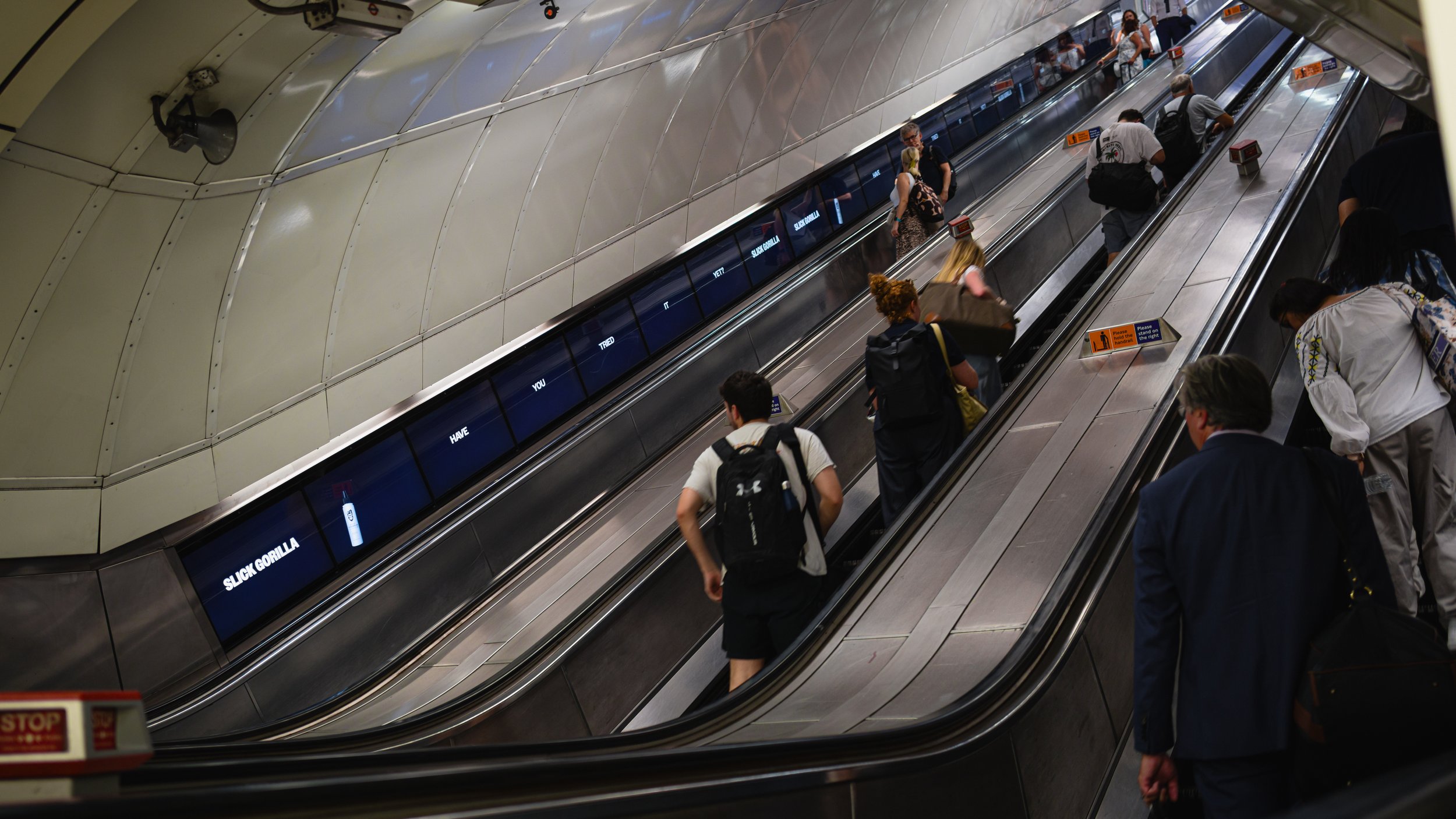 People riding down an escalator inside a subway station.