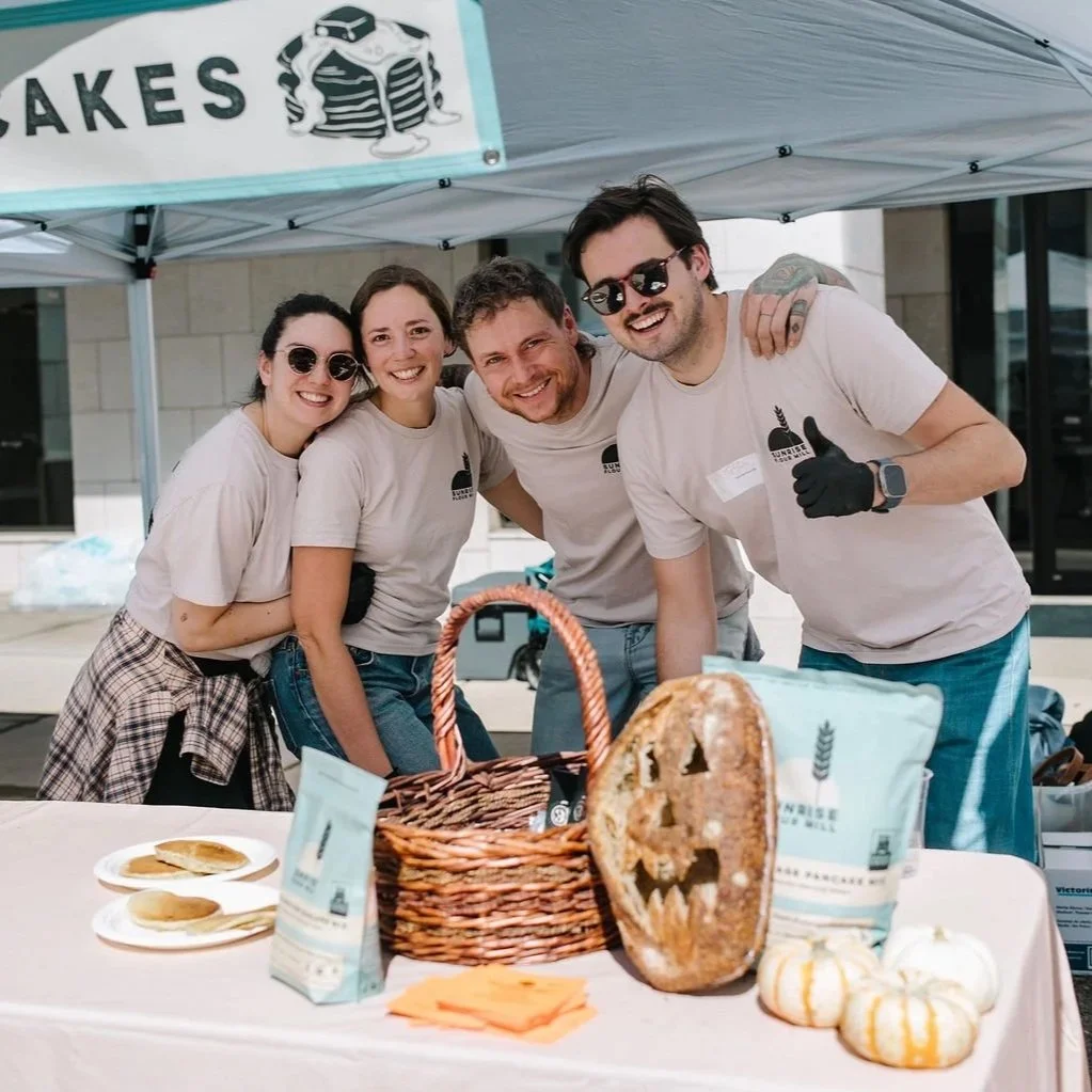 Four bakers smiling behind a loaf carved like a jack-o-lantern