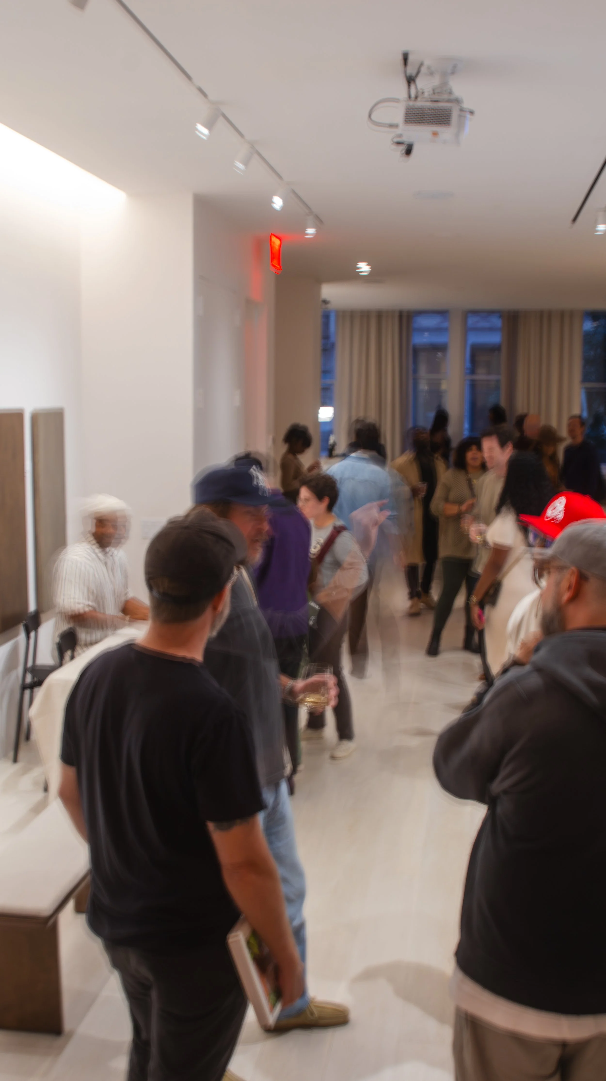 People gathering in a modern indoor space, engaging in conversations at social event or gathering.
