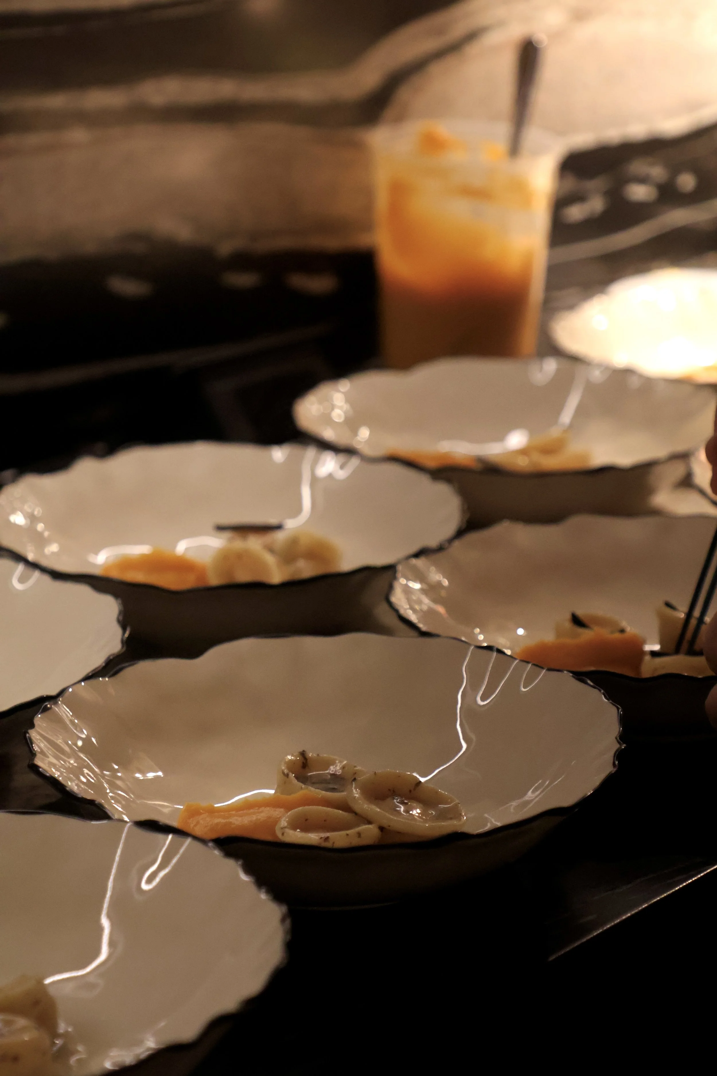 Close-up of a layered serving platter with seafood, pasta, and sauce, reflecting on a shiny surface.