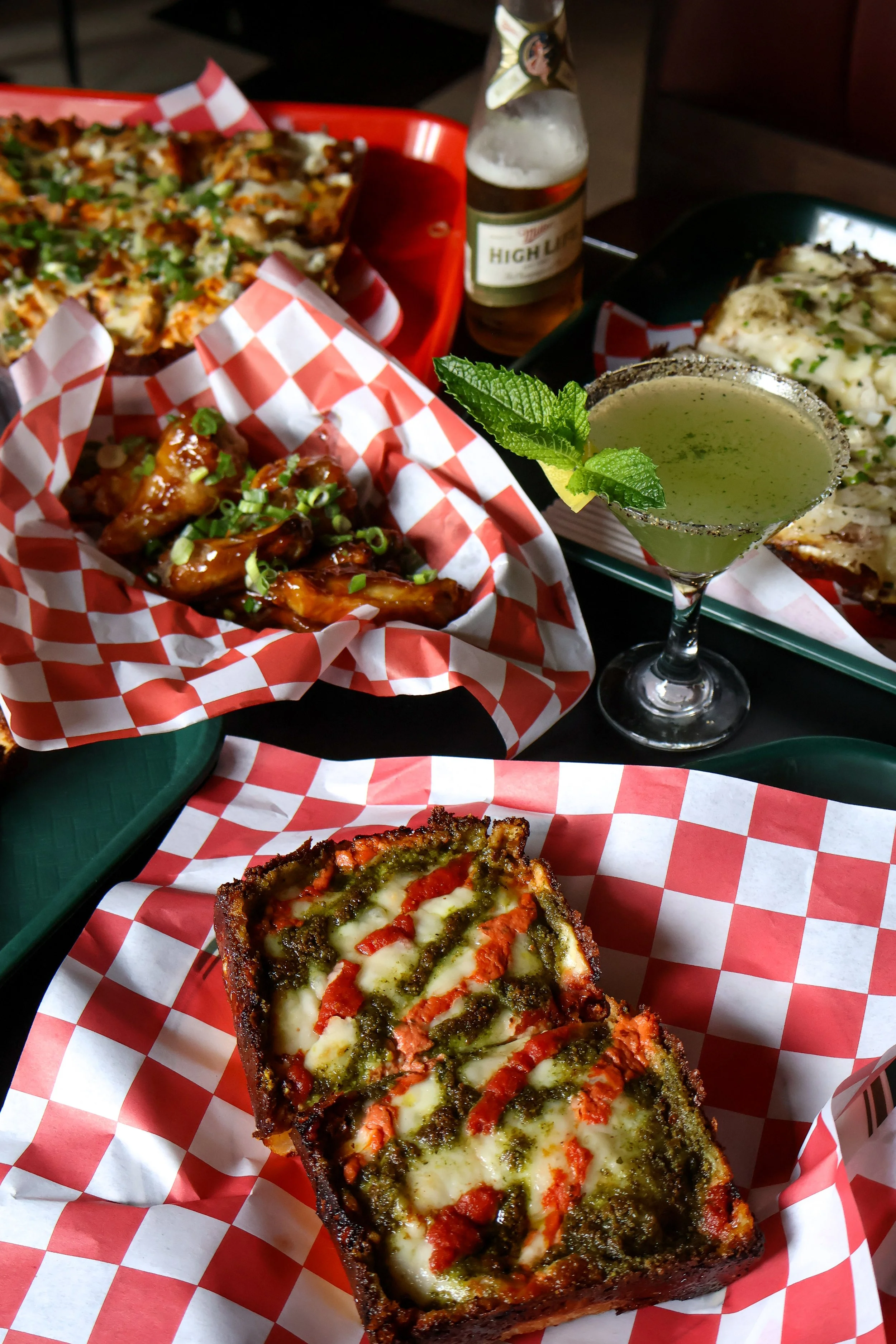 A slice of stuffed bread with cheese, tomato, and herbs on top, placed on red and white checkered paper.