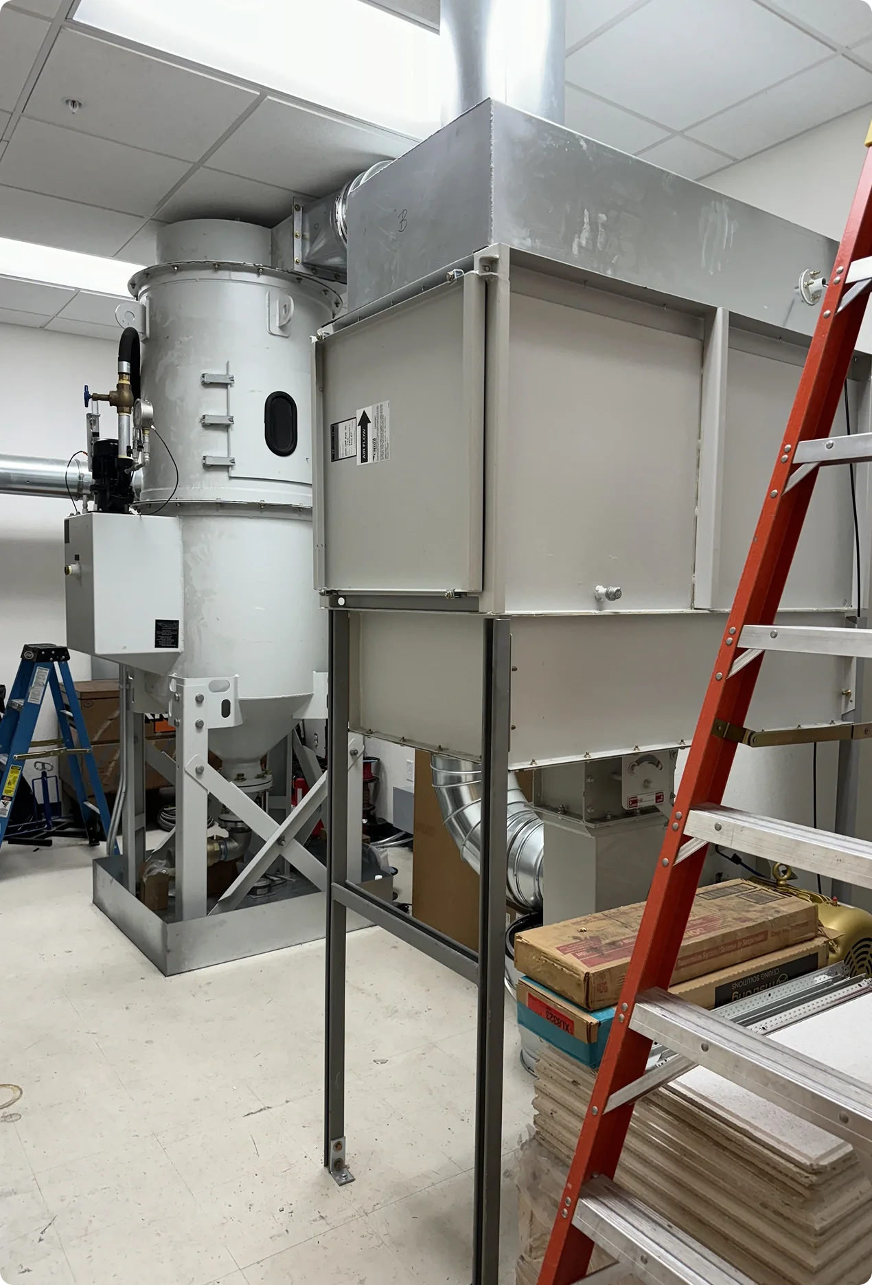 Industrial equipment installation in progress with scaffolding and tools inside a room.