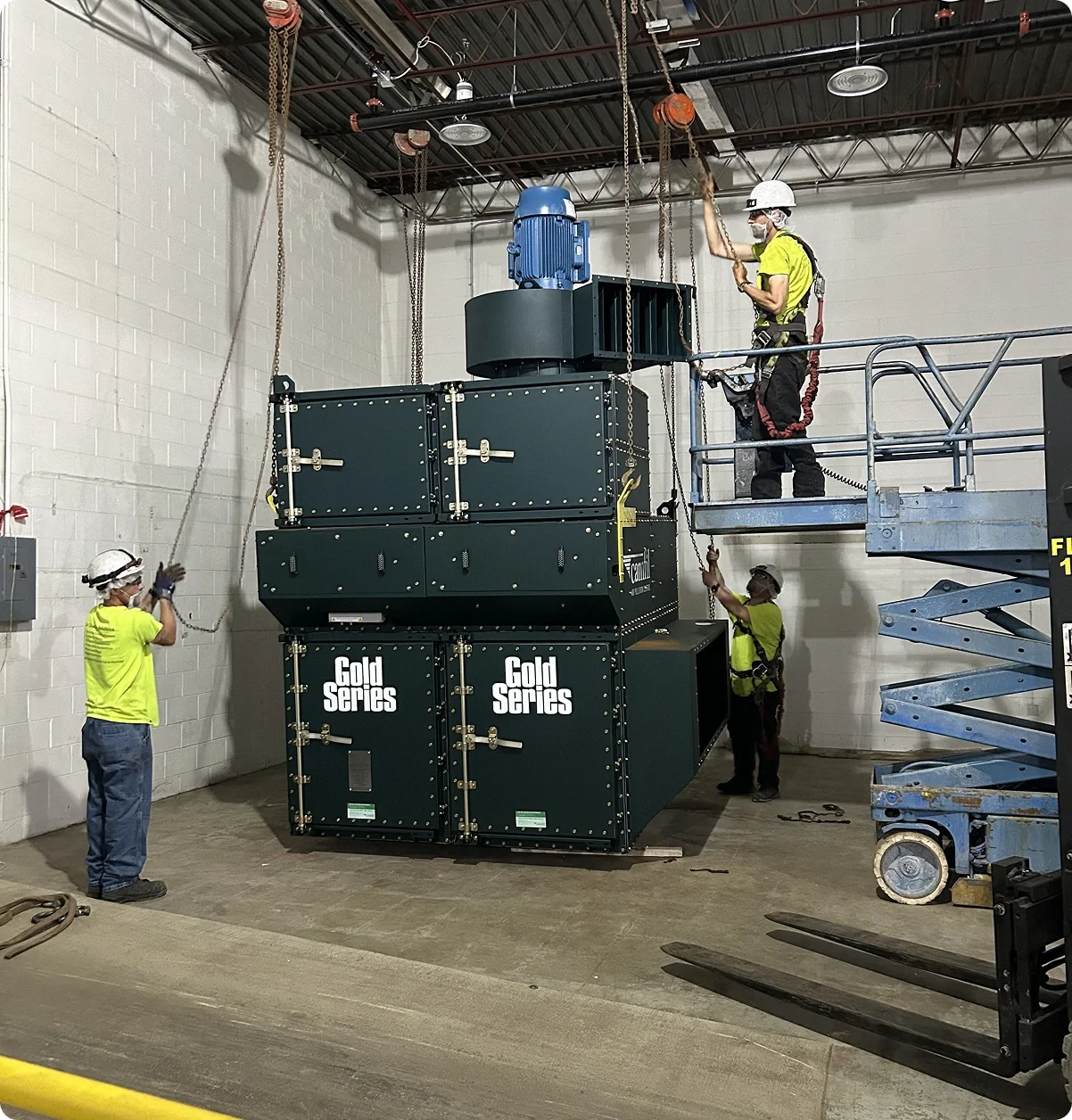 Four workers in safety gear install or inspect a large, industrial-sized generator with a label that reads 'Gold Series' inside a warehouse or factory.