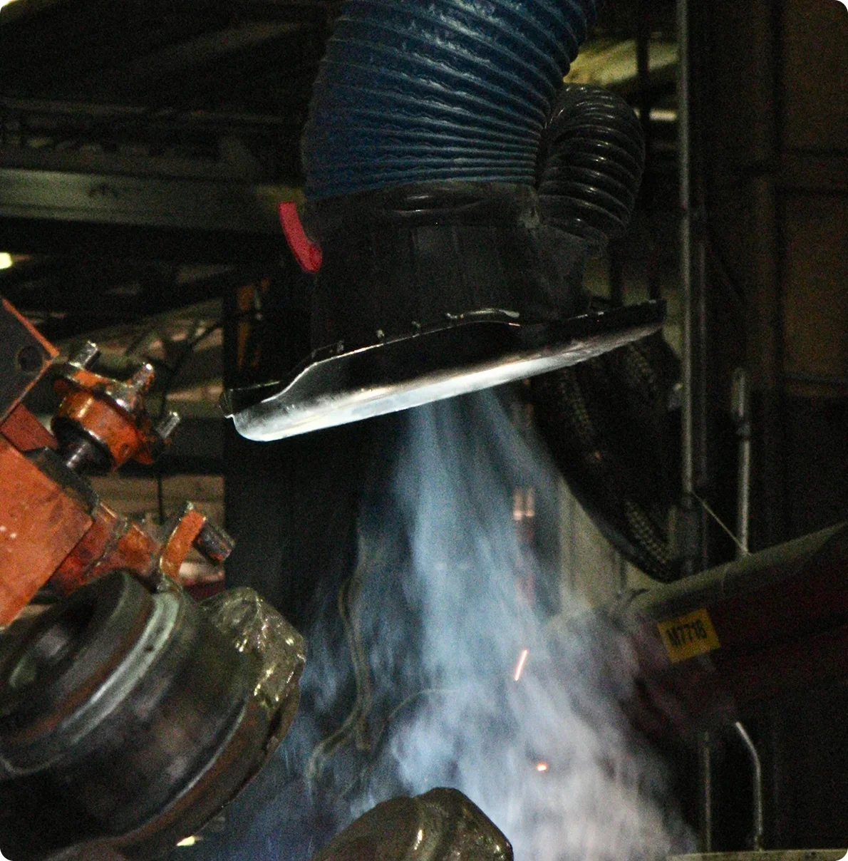 Welding process with bright sparks and smoke, close-up of welding machine and metal parts.