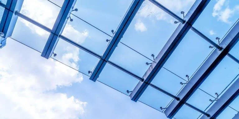 Glass ceiling with blue sky and clouds visible through the panels.