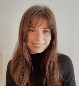 Young woman with long brown hair, smiling, wearing a black top.