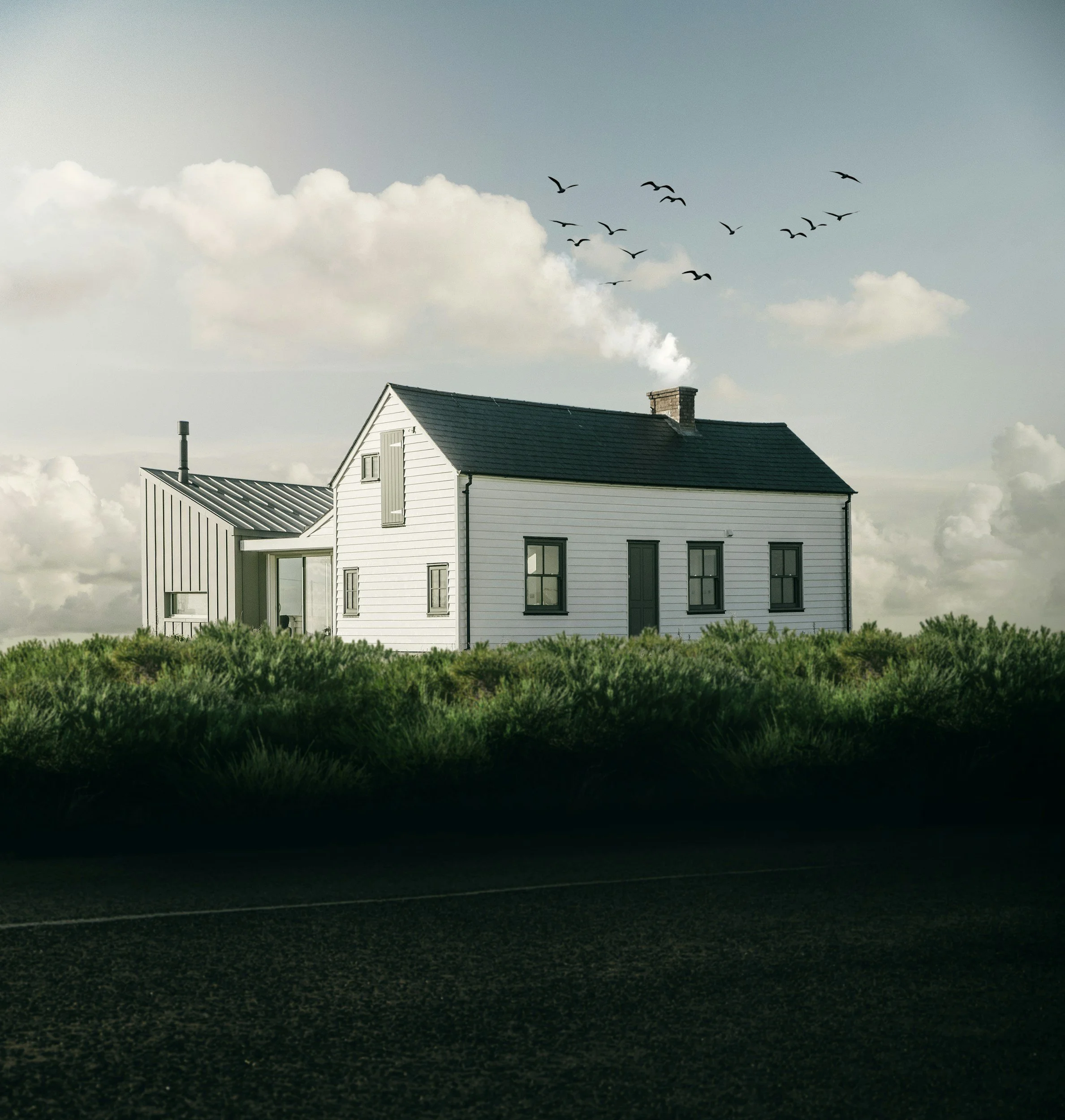 A white house with large windows and a sloped roof, set against a cloudy sky with a flock of birds flying overhead and a dark road in the foreground.