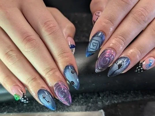 Close-up of hands with galaxy-themed nail art featuring swirling patterns, stars, and cosmic designs.