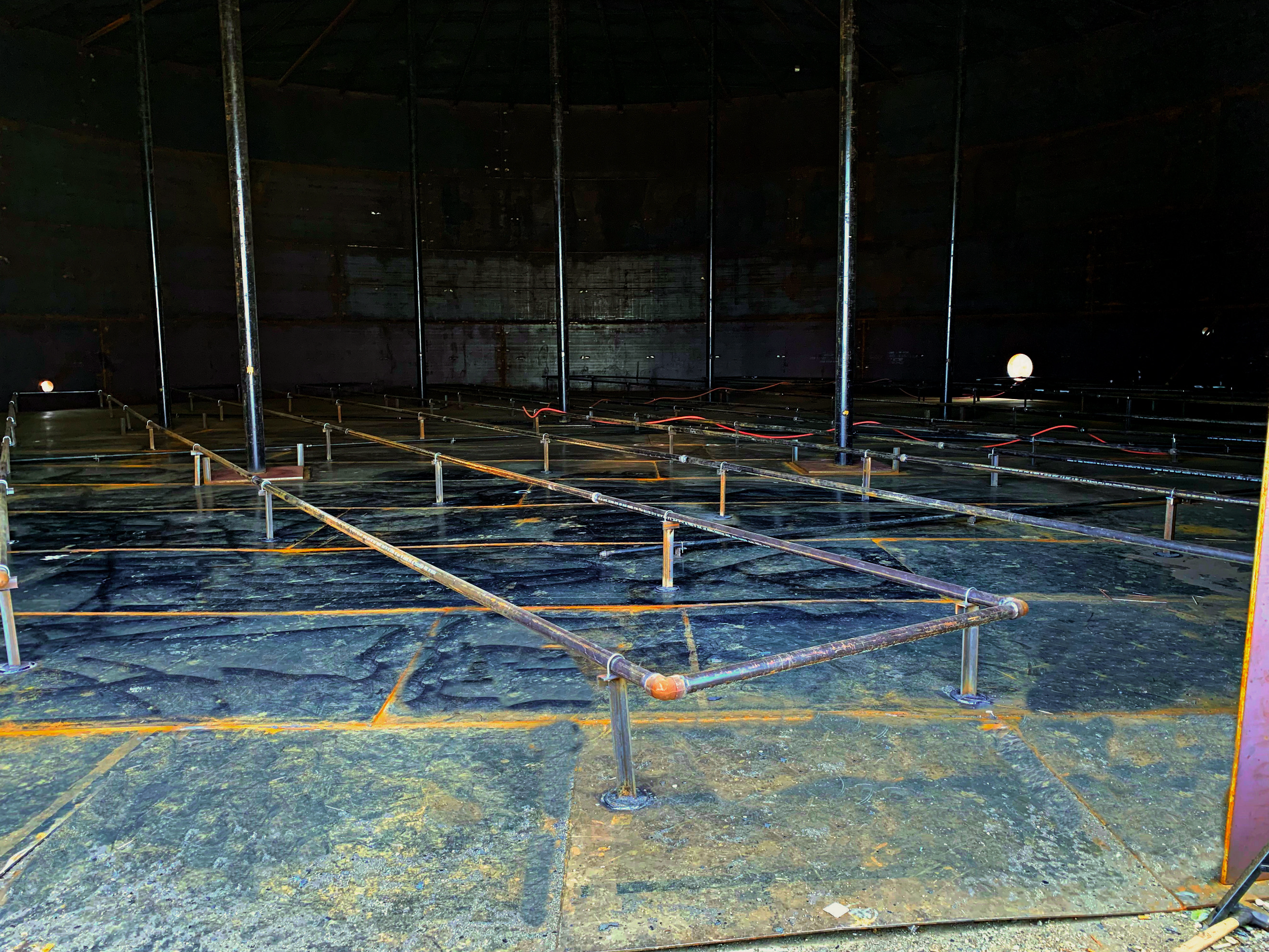 storage tank repair, dimly lit with faint light from outside.