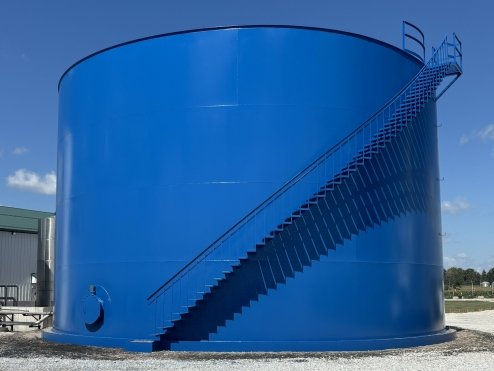 Large blue industrial storage tank with external staircase