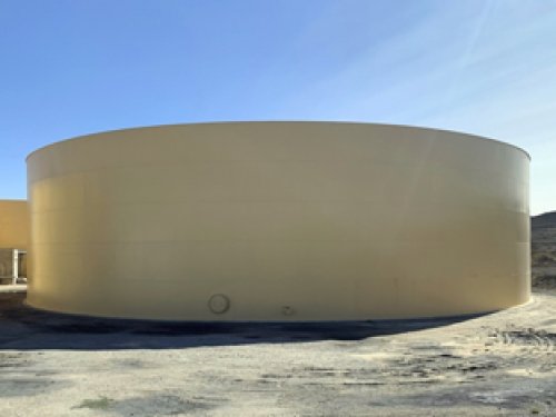 Large beige cylindrical tank outdoors with a clear blue sky in the background.