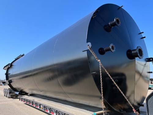Large black industrial storage tank on a flatbed truck