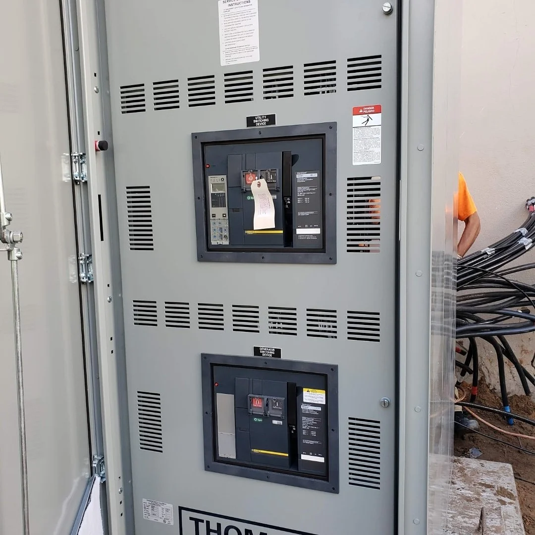 Outdoor electrical transformer with two circuit breakers installed on a gray metal enclosure.