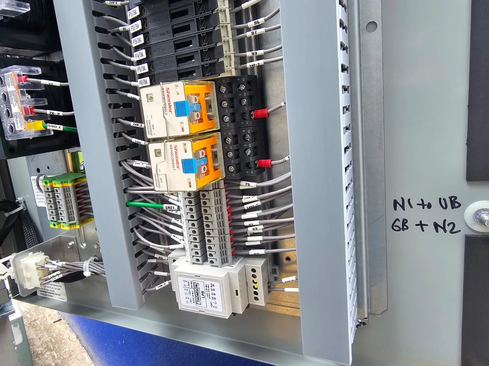 Electrical control panel with various wiring, relays, and circuit breakers.