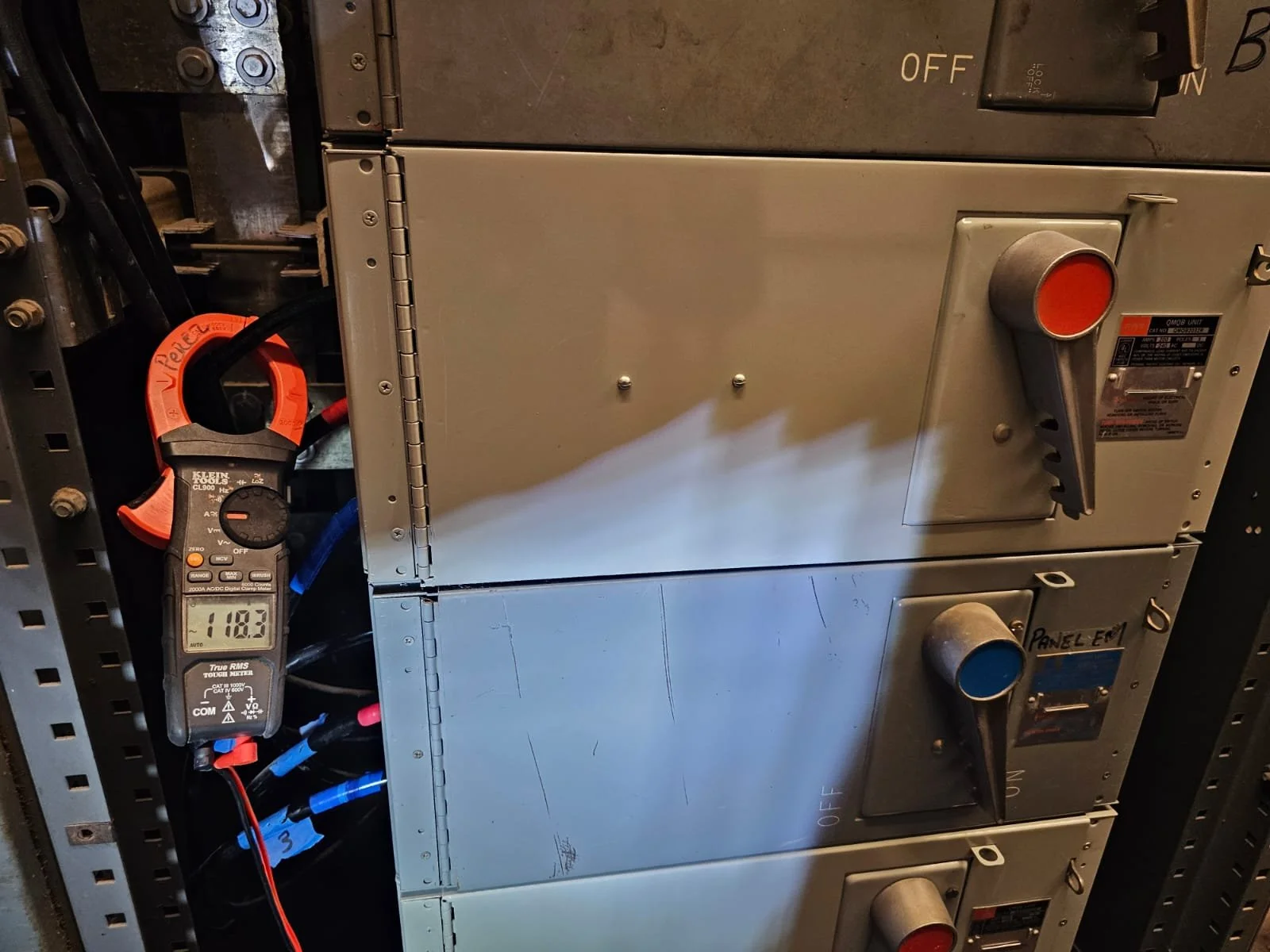 Electrical panels with switches, knobs, and a digital multimeter showing a reading of 118.3.