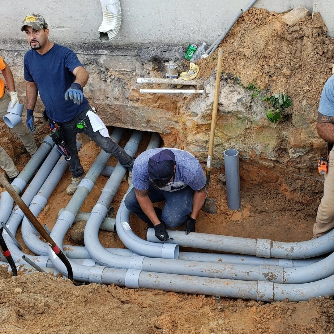 Installing underground pipes in a trench at a construction site.