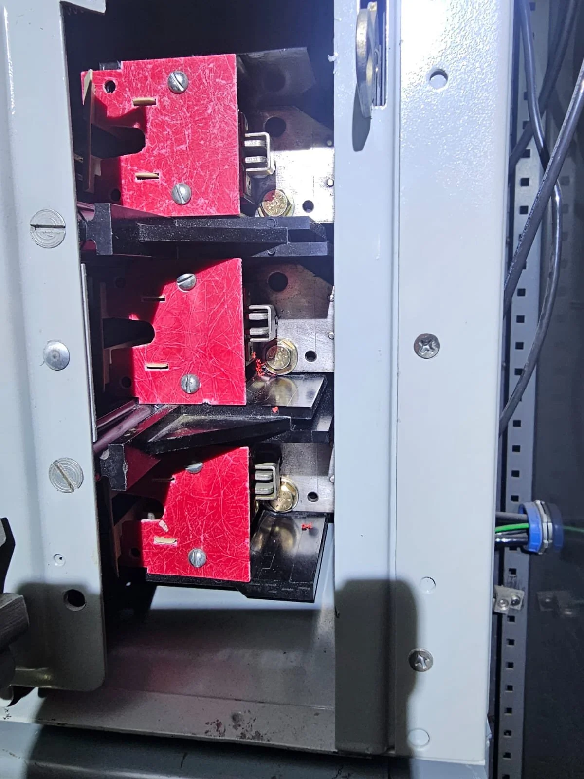 Close-up of an electrical panel with three large red circuit breakers, each secured.