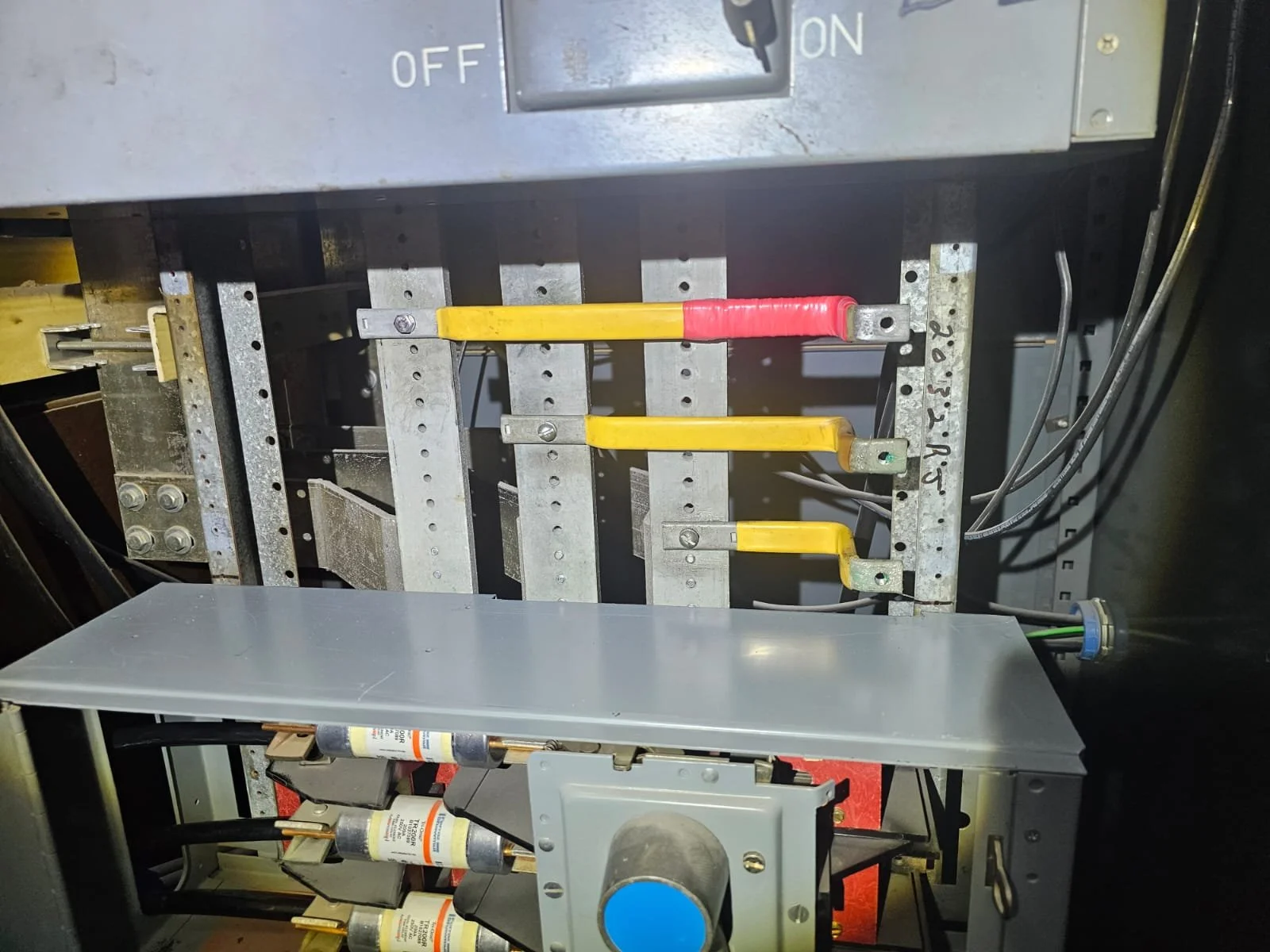 Inside view of an electrical panel with three yellow switches and wires connected to electrical components.
