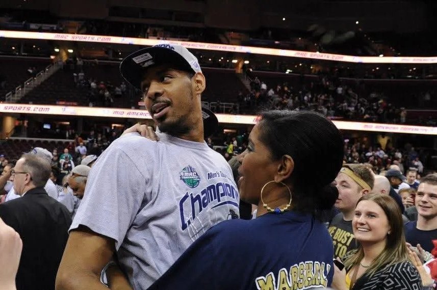 Zeke holding a woman in a sports arena, celebrating a victory, surrounded by a crowd of people.