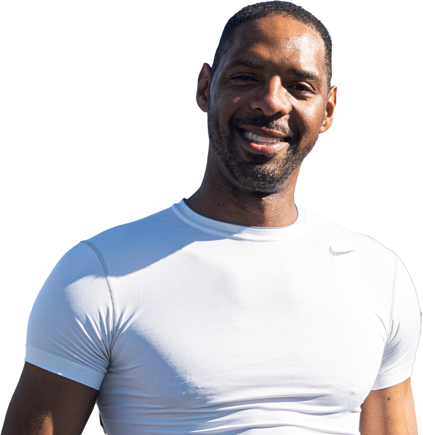 Zeke Marshall, smiling, wearing a white athletic t-shirt, standing outdoors with sunlight on his face.