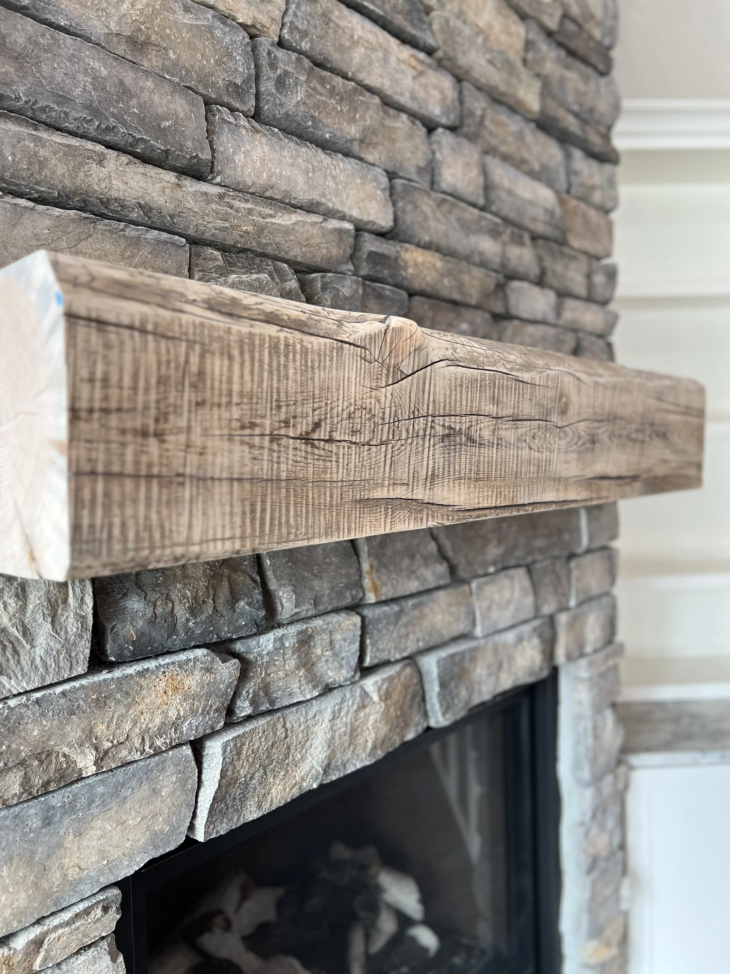 Close-up of a stone fireplace with a wooden mantel.