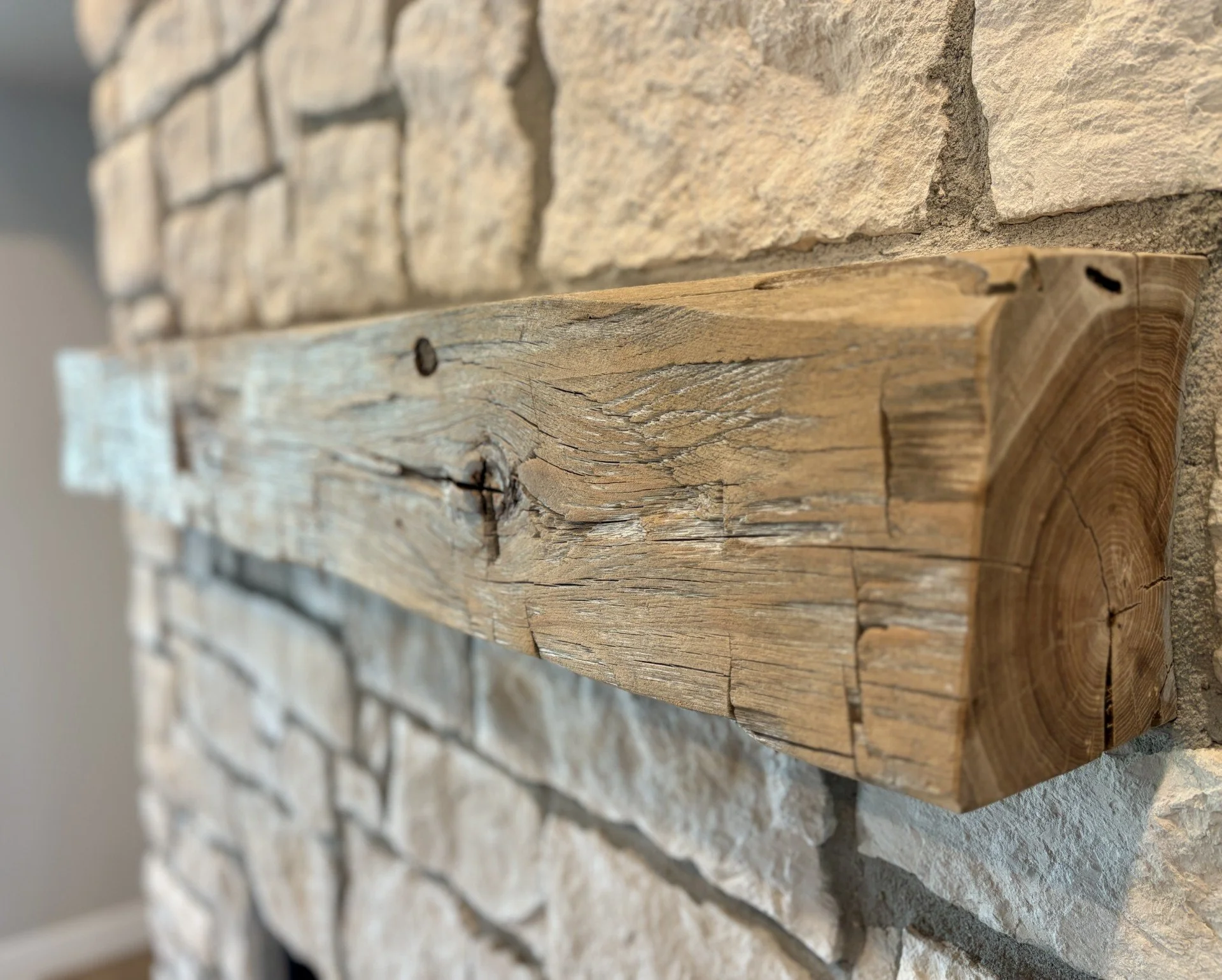 Close-up of a textured beige brick wall and a weathered wooden beam.