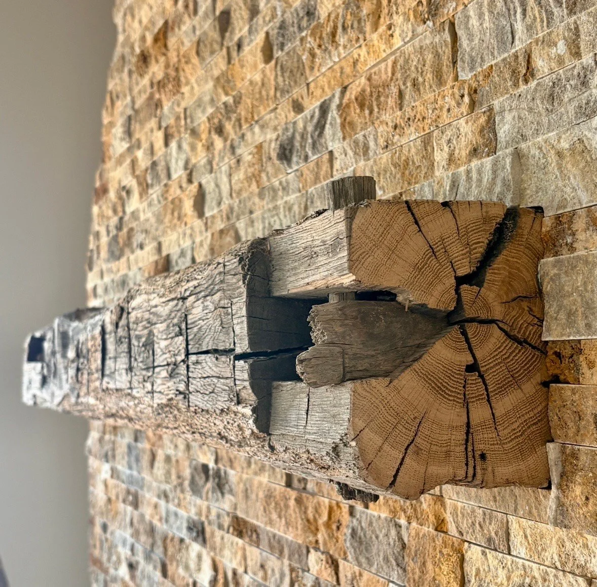 Close-up of stacked firewood logs on a brick wall background.