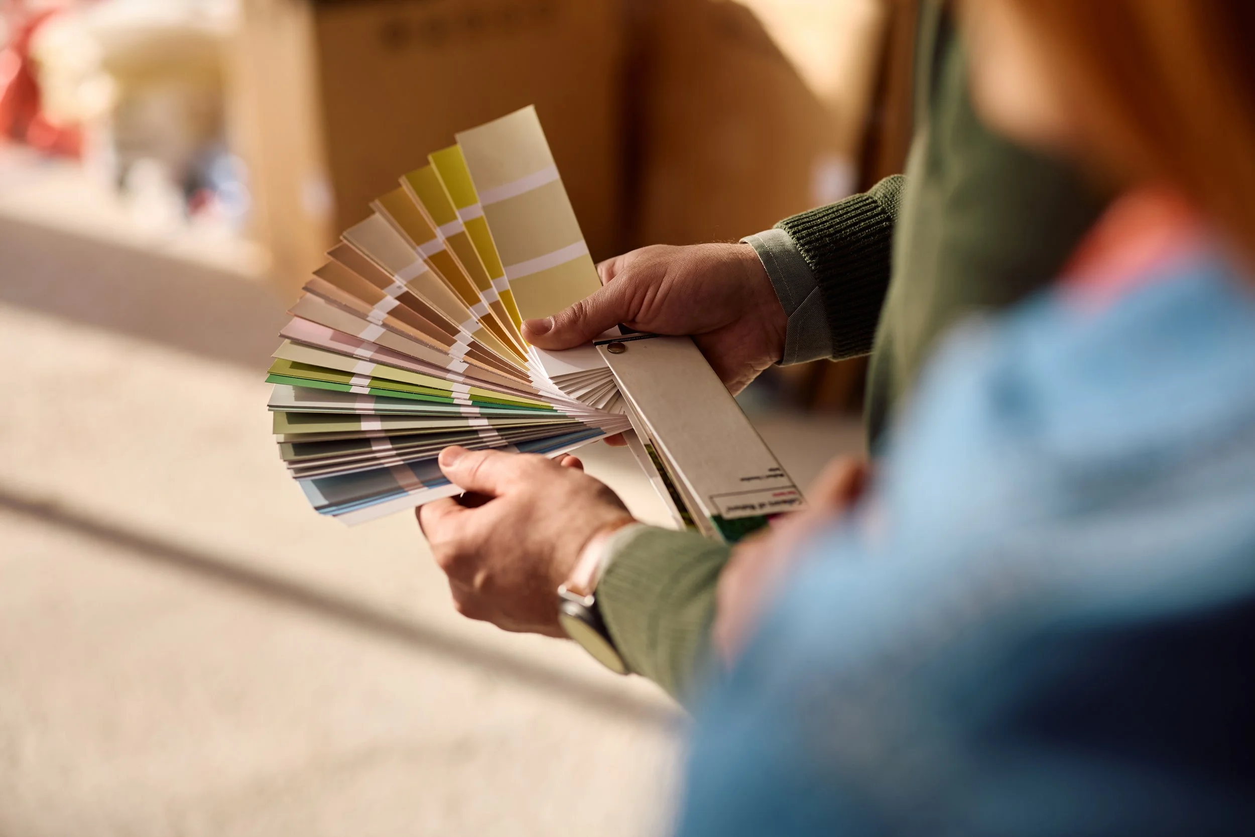 Person holding a fan deck of various paint color samples