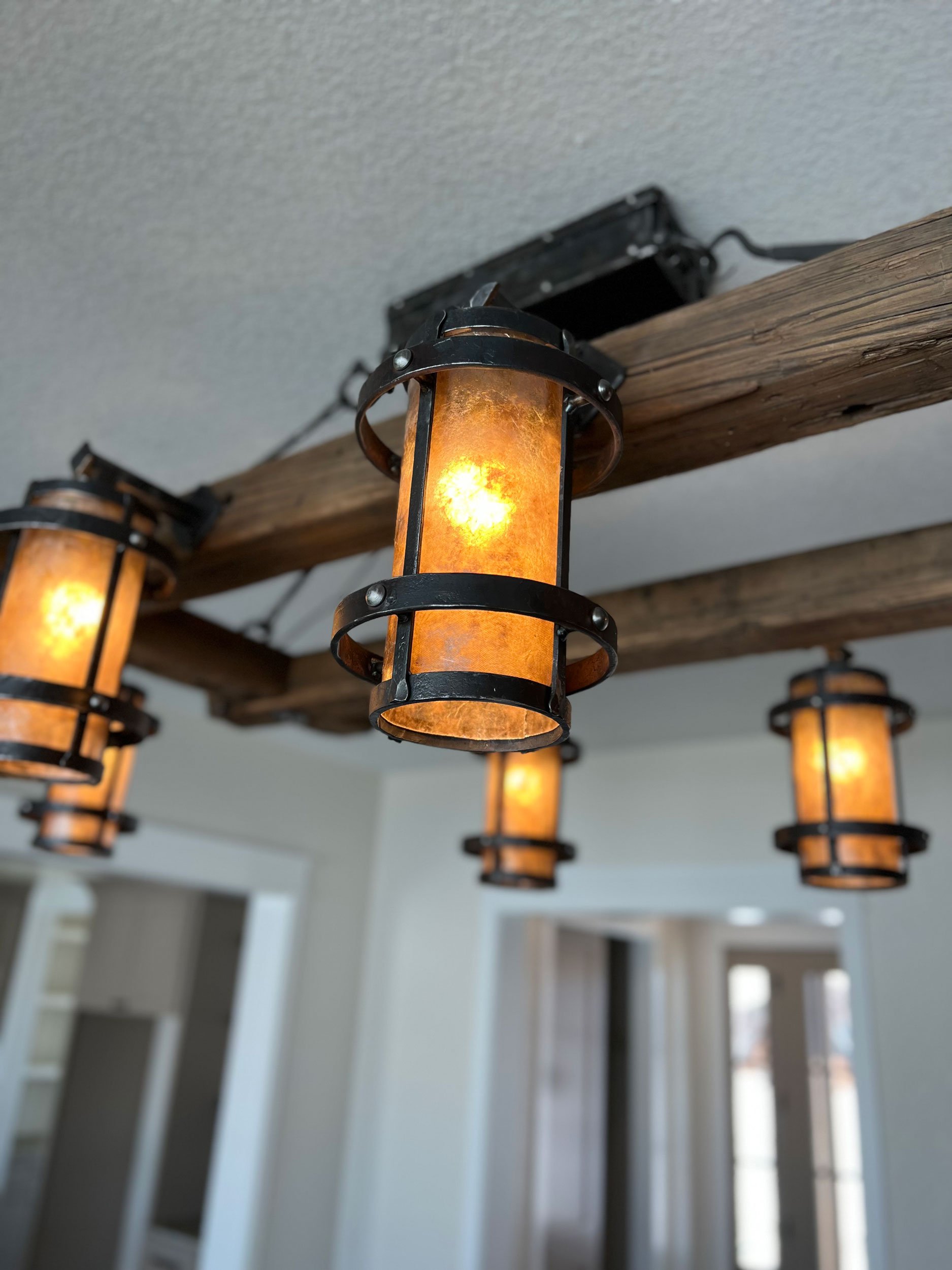 Close-up of decorative pendant lights hanging from a wooden beam ceiling.