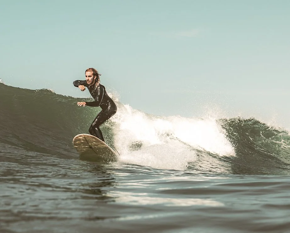 A woman in a black wetsuit surfing on a wave in the ocean.