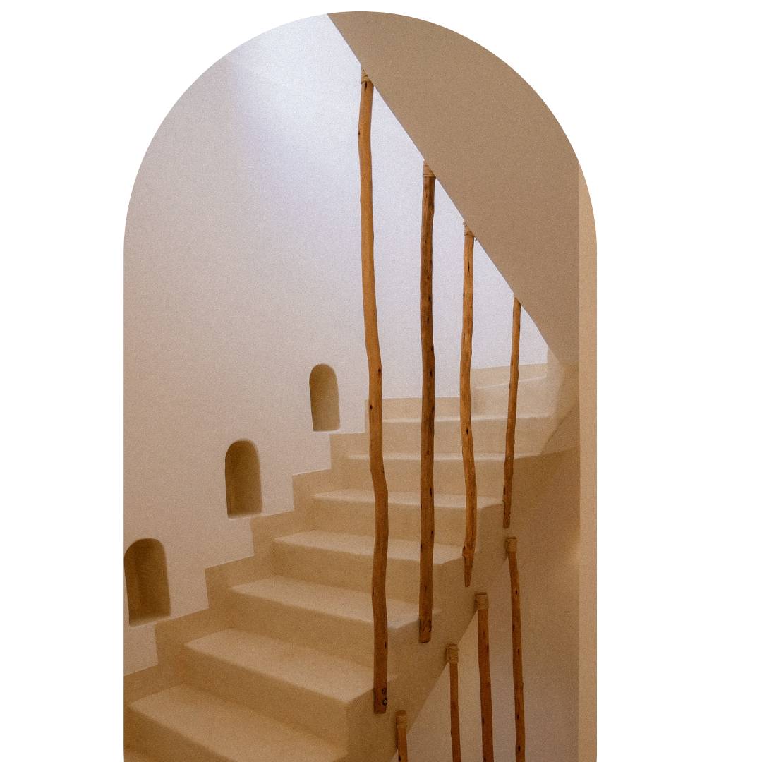 Interior view of a staircase with wooden railings and small arched nooks in the wall.