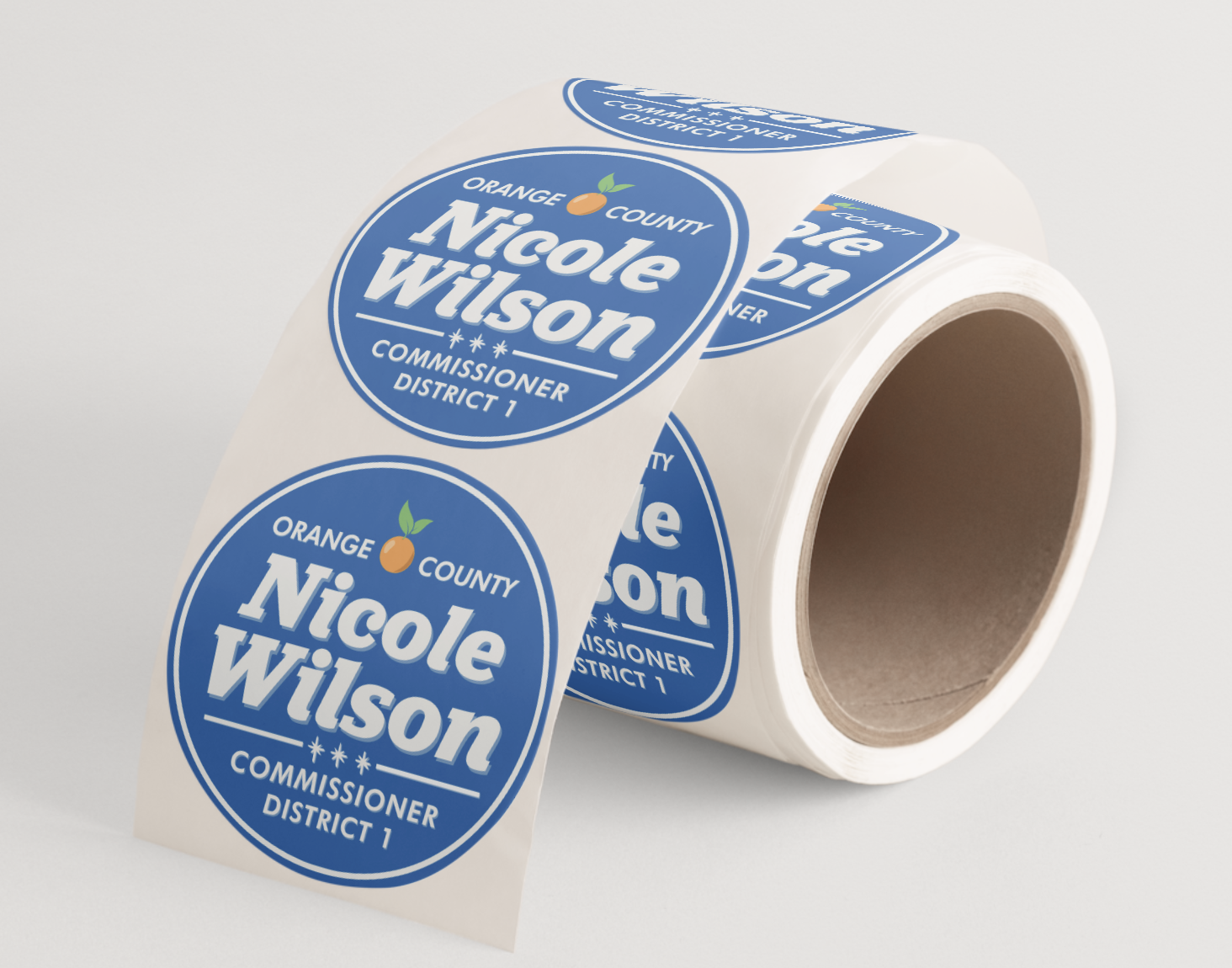 Roll of campaign stickers with blue labels reading "Nicole Wilson", "Orange County", and "Commissioner District 1" on a white background.