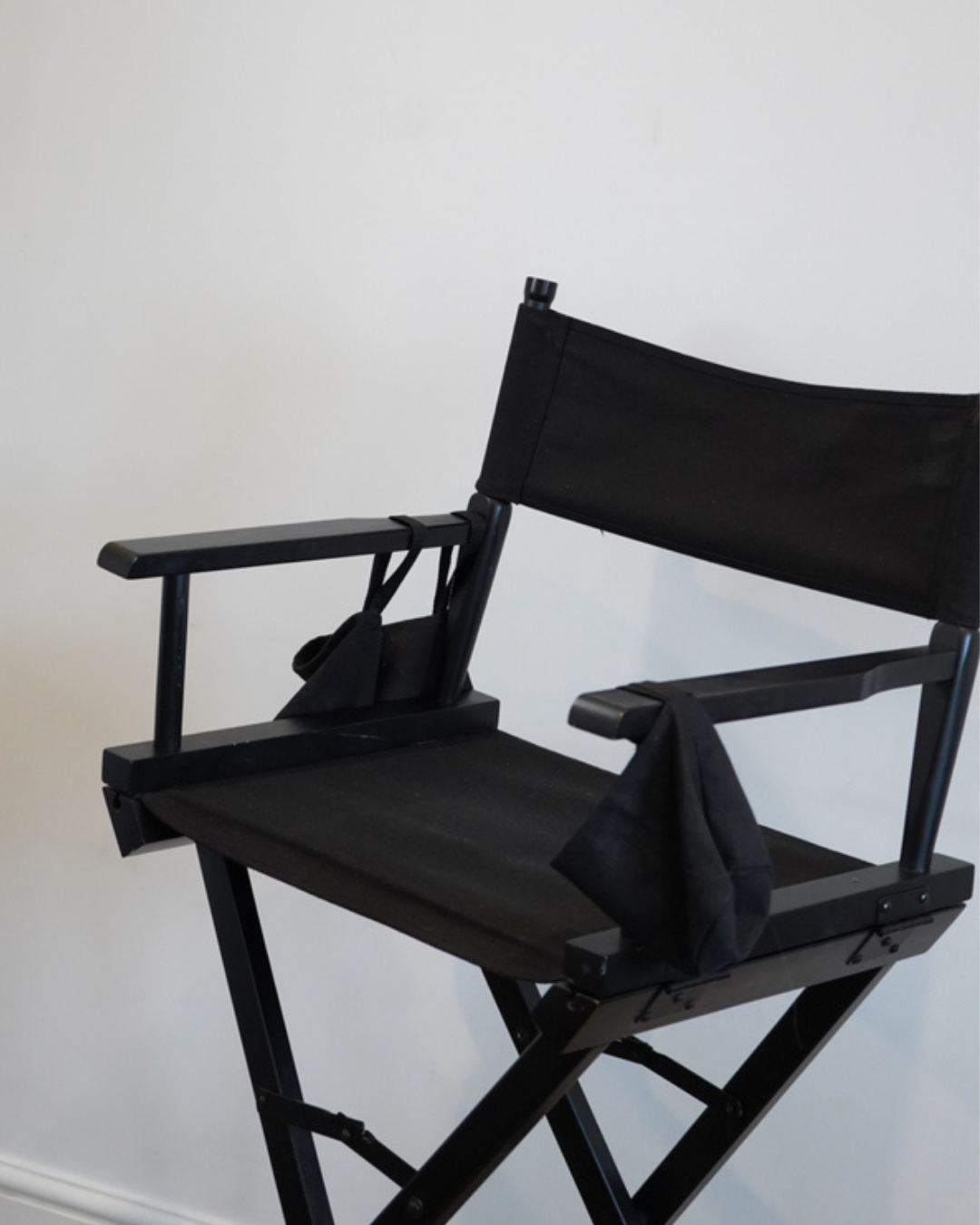 Black canvas director's chair with wooden armrests and folding X-frame legs