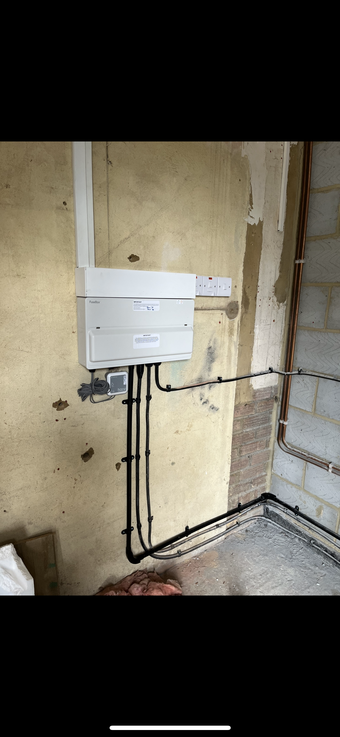 Electrical panel with wires and pipes in a room under renovation.