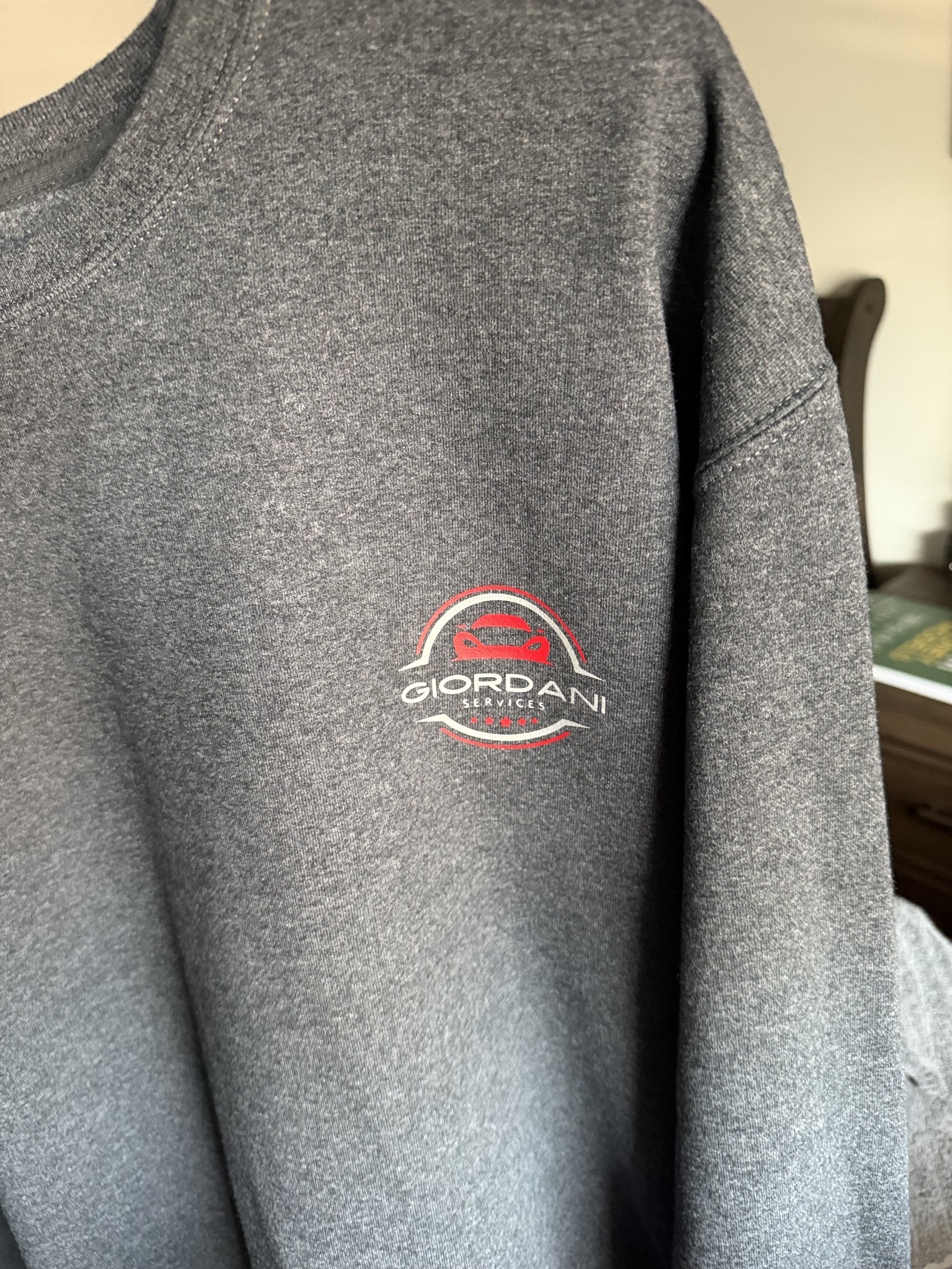 A shirt with DTF print close-up of a gray sweatshirt with a logo that reads 'Giordani Services' featuring a red and black car graphic.