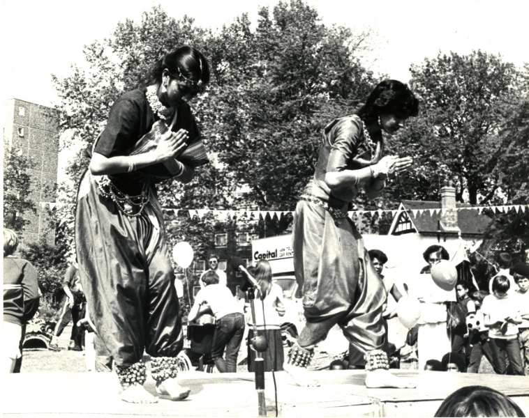 Indian dancers, Charlton House, 1980 Dancers in embroidered traditional Irish dresses perform outdoors at Charlton House, with spectators, bunting and residential buildings in the background.