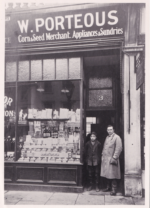 Black-and-white photograph, circa 1900, of a man and boy standing outside W. Porteous, a corn and seed merchant at 3 Eltham High Street, Eltham.