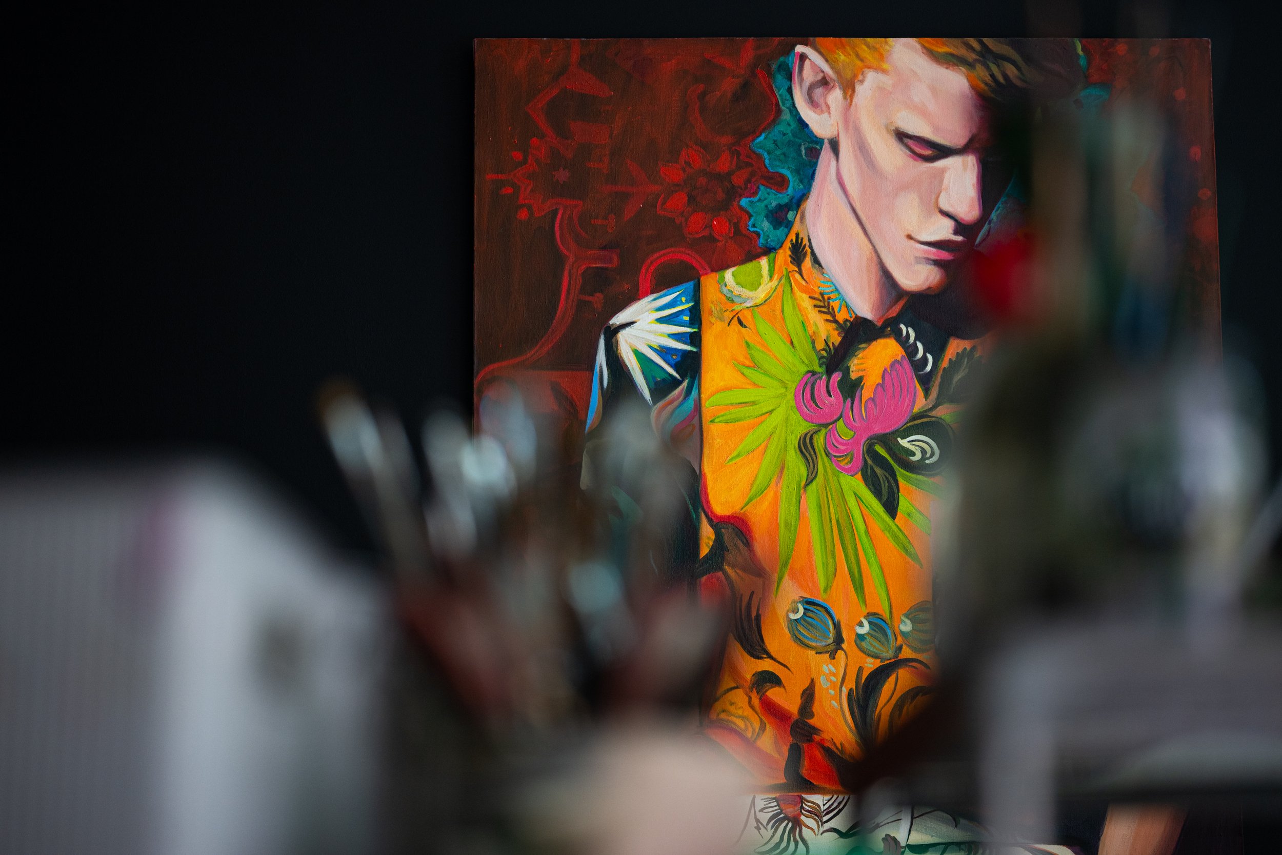 Colorful painting of a woman with stylized hair, wearing a vibrant, patterned outfit, displayed on an art gallery wall.