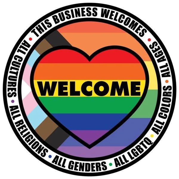 A circular design featuring a rainbow-colored heart with the word "WELCOME" inside. The outer ring contains text stating "THIS BUSINESS WELCOMES ALL CULTURES, ALL RELIGIONS, ALL GENDERS, ALL COLORS, ALL LGBTQ+" with multicolored dots separating each phrase.